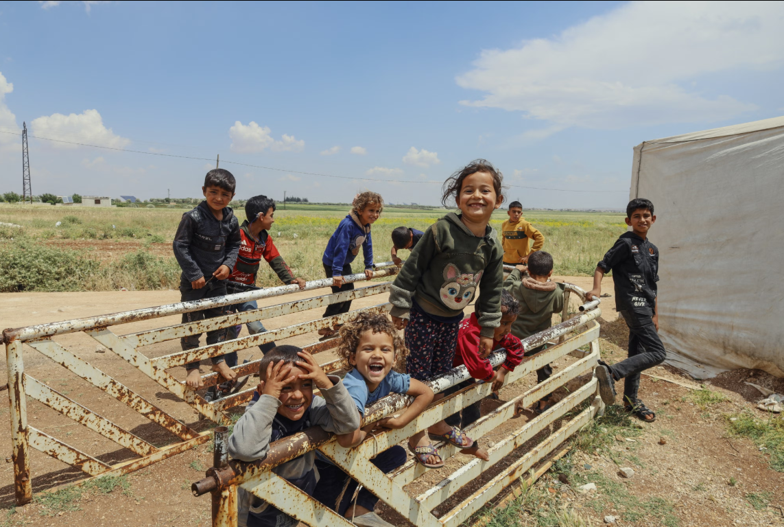 Displaced Syrian children laugh and play among temporary tents set up after the fall of the Bashar al-Assad government near Idlib, Syria